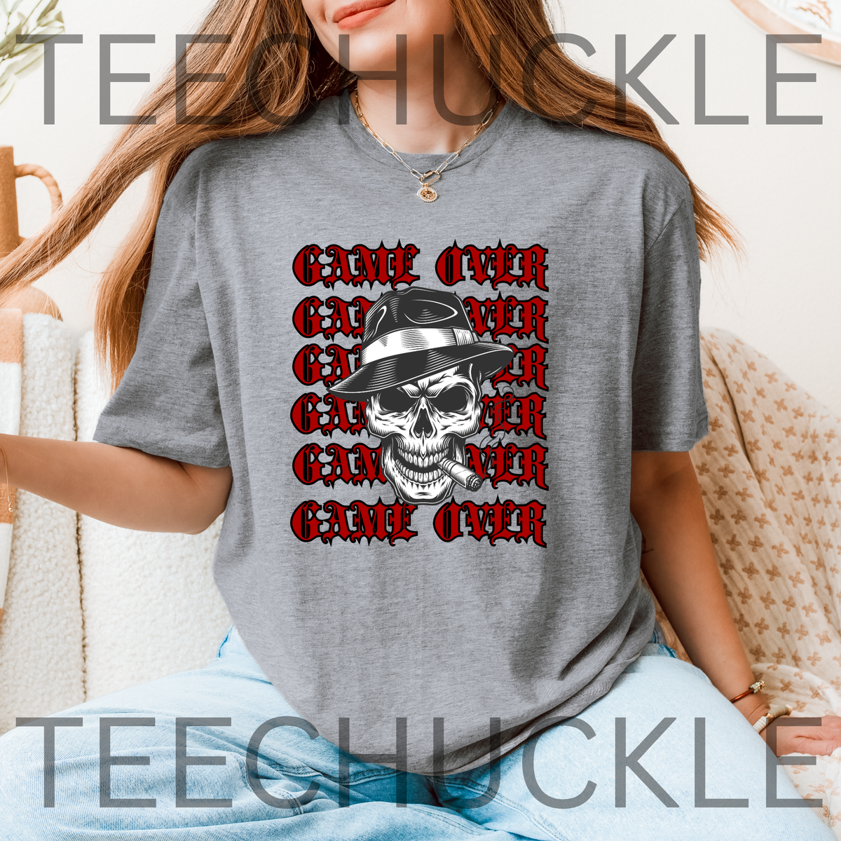 A woman wearing a grey short-sleeve graphic T-shirt, featuring a skull in a hat smoking a cigerette design with the text 'GAME OVER' repeatedly stacked. Decorative vintage microphones and a microphone and comedy masks appear at the top left and bottom right.