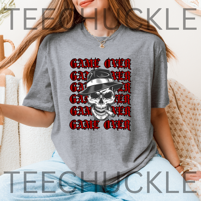 A woman wearing a grey short-sleeve graphic T-shirt, featuring a skull in a hat smoking a cigerette design with the text 'GAME OVER' repeatedly stacked. Decorative vintage microphones and a microphone and comedy masks appear at the top left and bottom right.