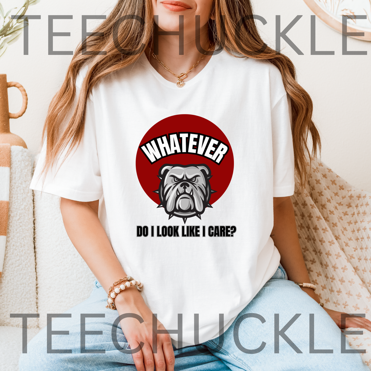 A woman wearing a white t-shirt in an inddor setting. The shirt has a red circle with a bulldog on it and the text that reads " WHATEVER, DO I LOOK LIKE I CARE"