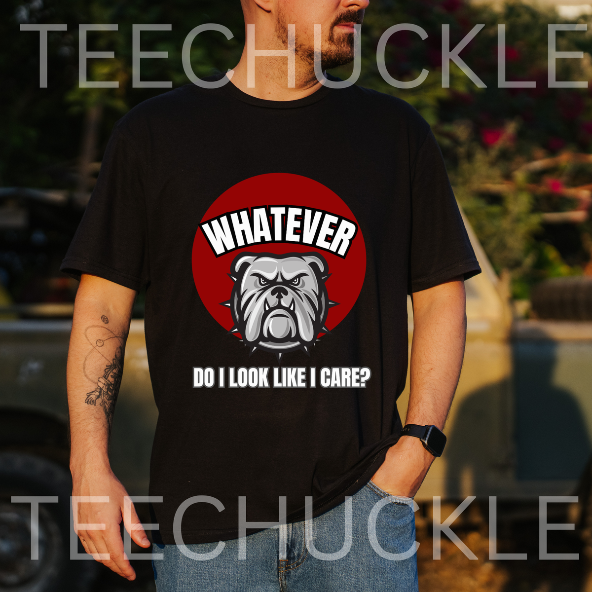 A man wearing a black t-shirt standing outdoors. The shirt has a red circle with a bulldog on it and the text that reads " WHATEVER, DO I LOOK LIKE I CARE"