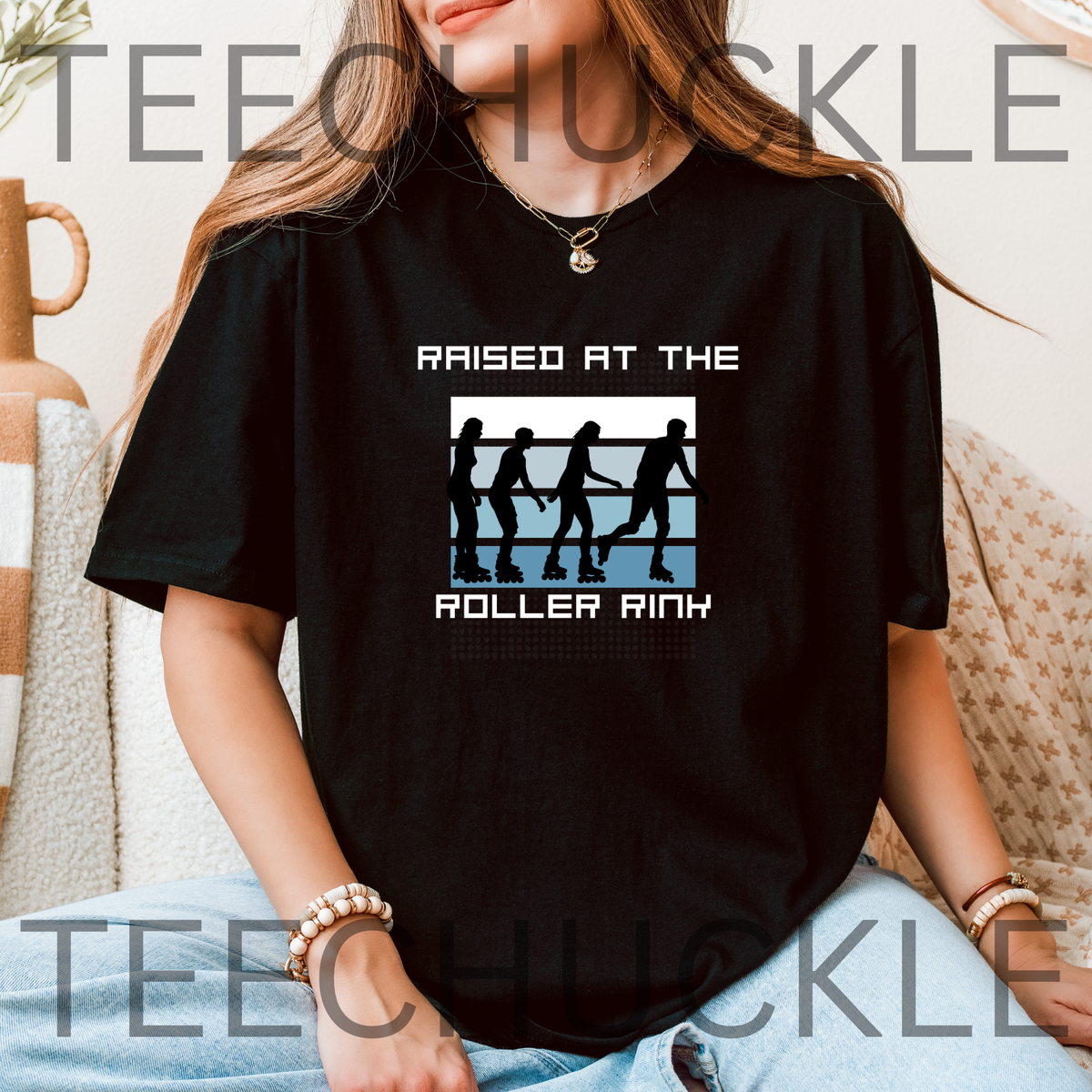 A woman wearing a black graphic t-shirt with a roller rink design and the text 'RAISED AT THE ROLLER RINK'. 