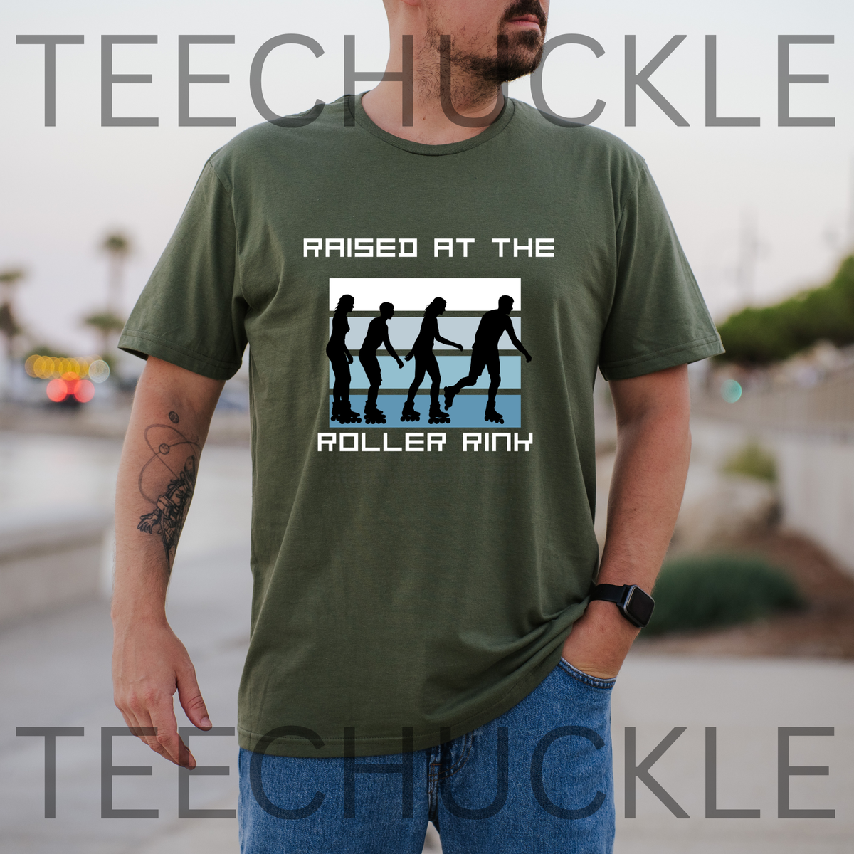 A man wearing a green graphic t-shirt with a 'Raised at the Roller Rink' design, standing outdoors with a blurred background. 