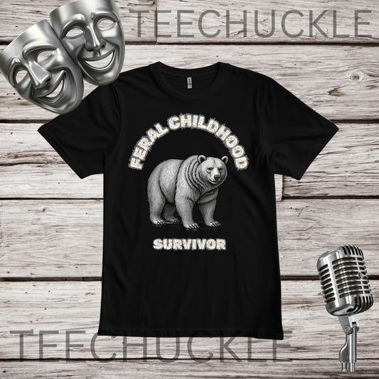 A black short-sleeve graphic T-shirt laid flat on a rustic wood plank background, featuring a white bear illustration with the words 'Feral Childhood Survivor.' Silver theater masks and a vintage microphone appear as decorative props
