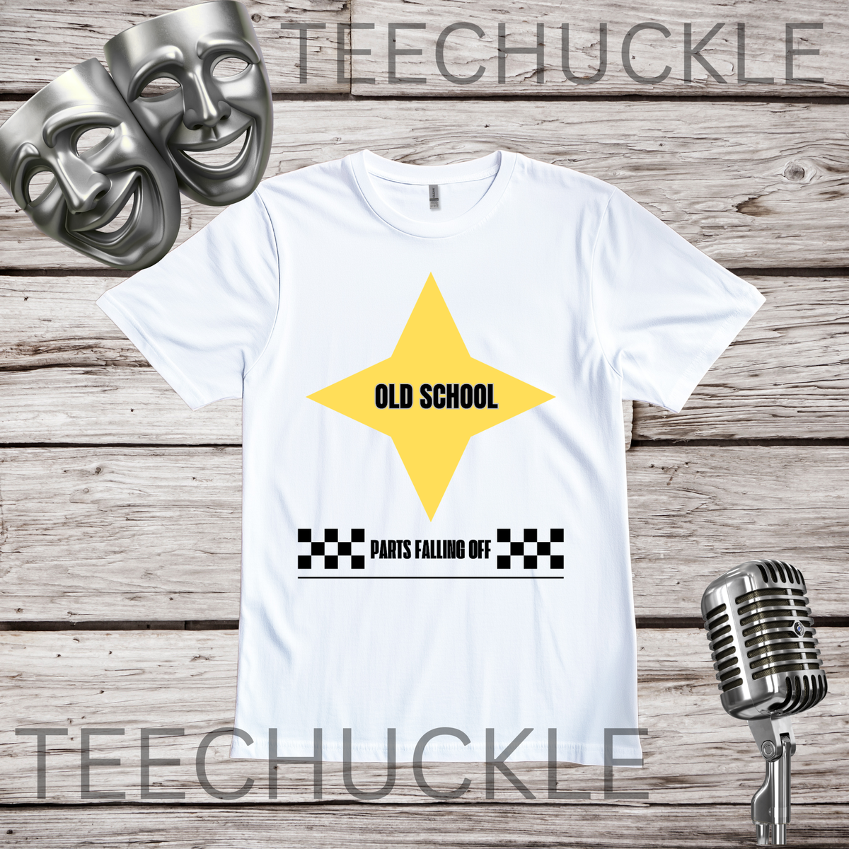 A white short-sleeve graphic T-shirt laid flat on a rustic wood plank background, with two silver comedy masks and a vintage microphone as props. The shirt has a large yellow star graphic with the words 'OLD SCHOOL' in black, plus a black-and-white checkered bar and the phrase 'PARTS FALLING OFF' below.