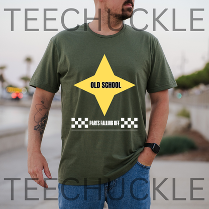 A man wearing a green t-shirt with a yellow and white graphic that reads 'OLD SCHOOL' and 'PARTS FALLING OFF', and the background is a blurred outdoor street scene.