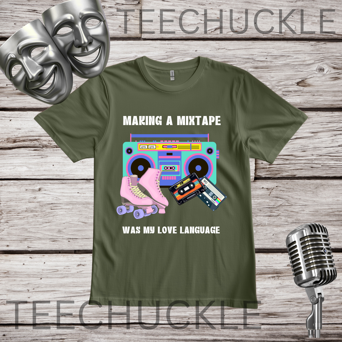 A green graphic t-shirt displayed on a rustic wood background, featuring a retro boombox, cassette tapes, and a pink roller skate graphic with the text 'MAKING A MIXTAPE WAS MY LOVE LANGUAGE'. The t-shirt is styled with silver theater masks, a vintage microphone.