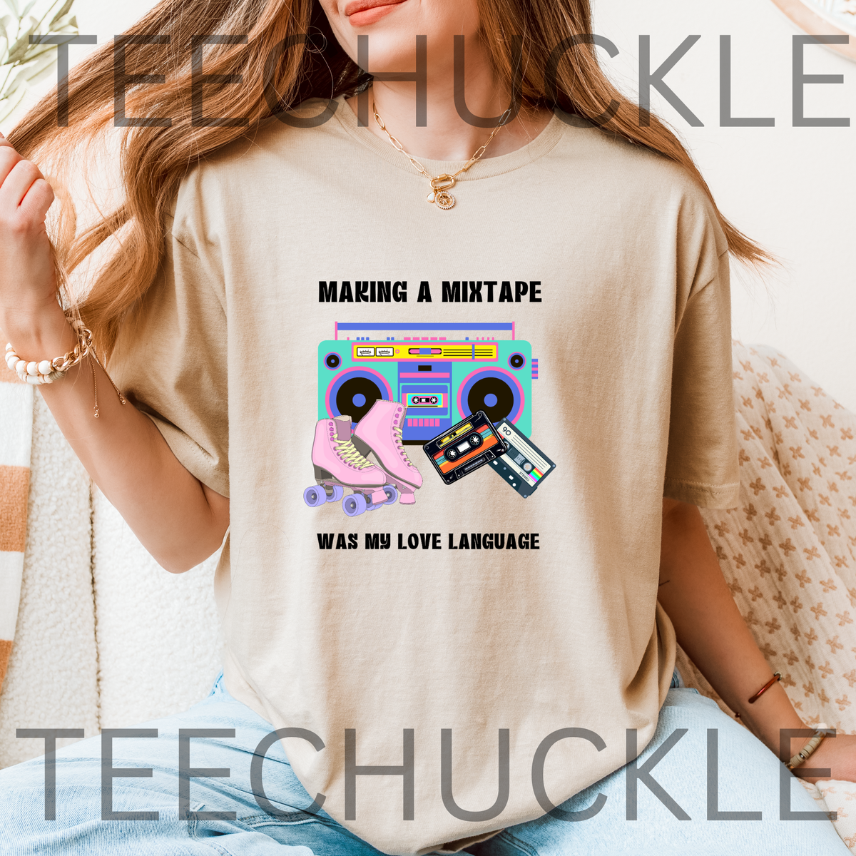 A woman wearing a sand graphic t-shirt with a retro 80s boombox, roller skate, and cassette tape design with the text 'MAKING A MIXTAPE WAS MY LOVE LANGUAGE'.