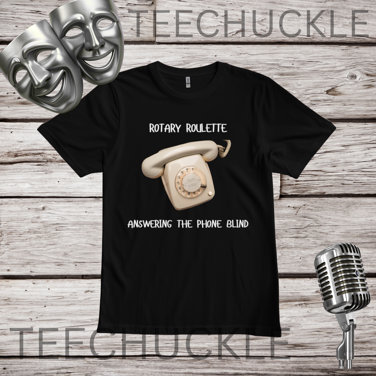 A black short-sleeve graphic t-shirt featuring a retro cream rotary telephone and the text 'ROTARY ROULETTE' and 'ANSWERING THE PHONE BLIND'. The shirt is displayed on a rustic wood background with silver theater masks, a vintage microphone.