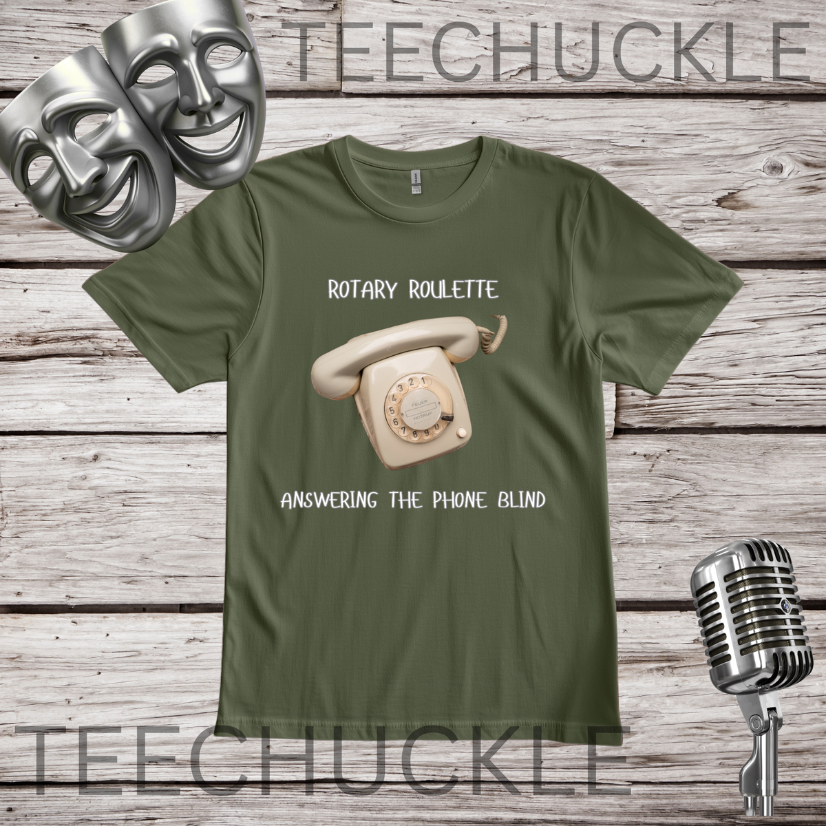A green graphic t-shirt featuring a retro rotary phone illustration and the text 'ROTARY ROULETTE' and 'ANSWERING THE PHONE BLIND'. The t-shirt is displayed on a rustic wooden background with silver comedy and microphone props.