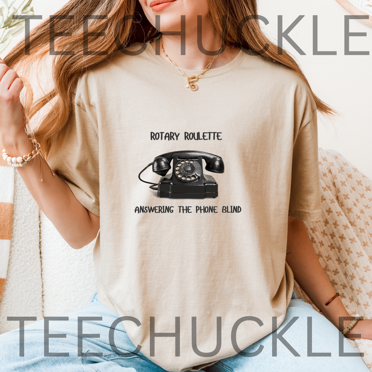 A woman wearing a sand graphic t-shirt with a black rotary telephone print and the text 'ROTARY ROULETTE' and 'ANSWERING THE PHONE BLIND'.