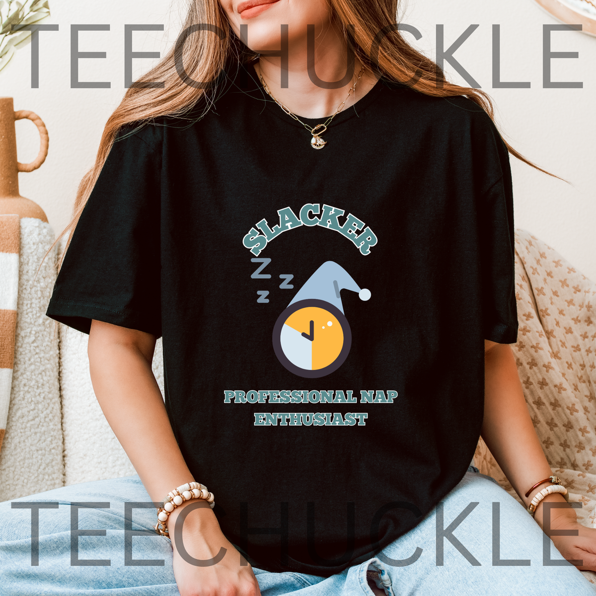 A woman wearing a black graphic t-shirt with a 'Slacker professional nap enthusiast' sleeping clock design, sitting on a beige couch. 