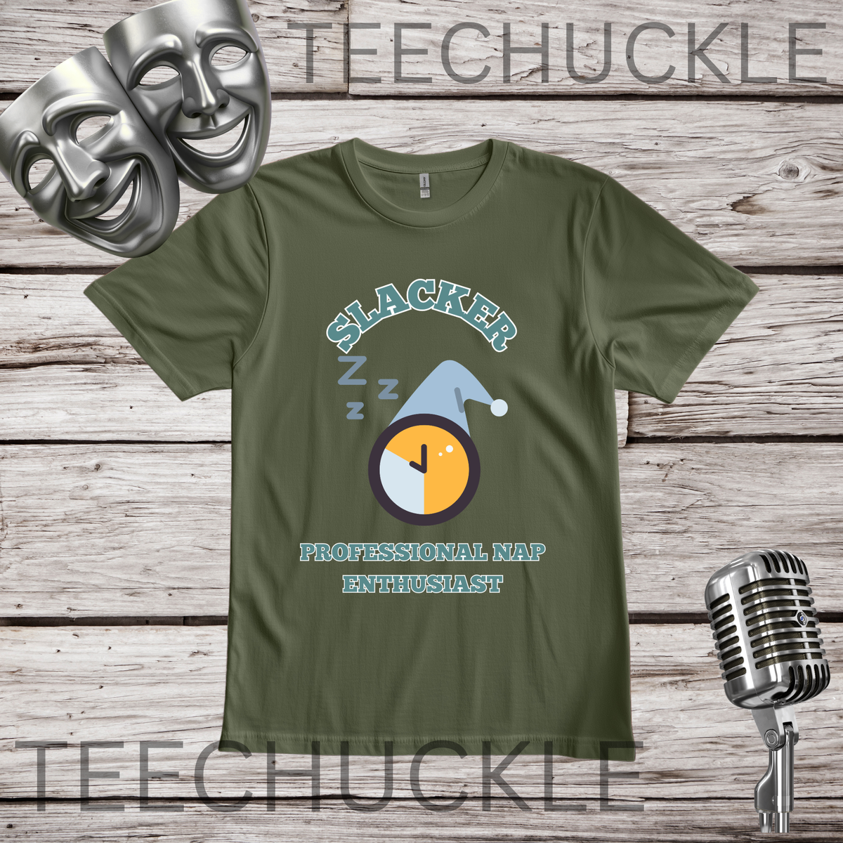 A green graphic t-shirt displayed on a rustic wood background, featuring a 'Slacker Professional Nap Enthusiast' design with a sleeping clock and hat. The image includes decorative props like a silver comedy mask, a vintage microphone
