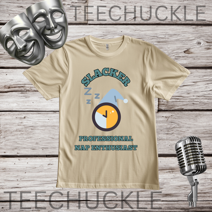 A sand graphic t-shirt displayed on a rustic wood background, featuring a 'Slacker Professional Nap Enthusiast' design with a clock and Santa hat. The image includes decorative props like silver comedy and tragedy masks, a vintage microphone.