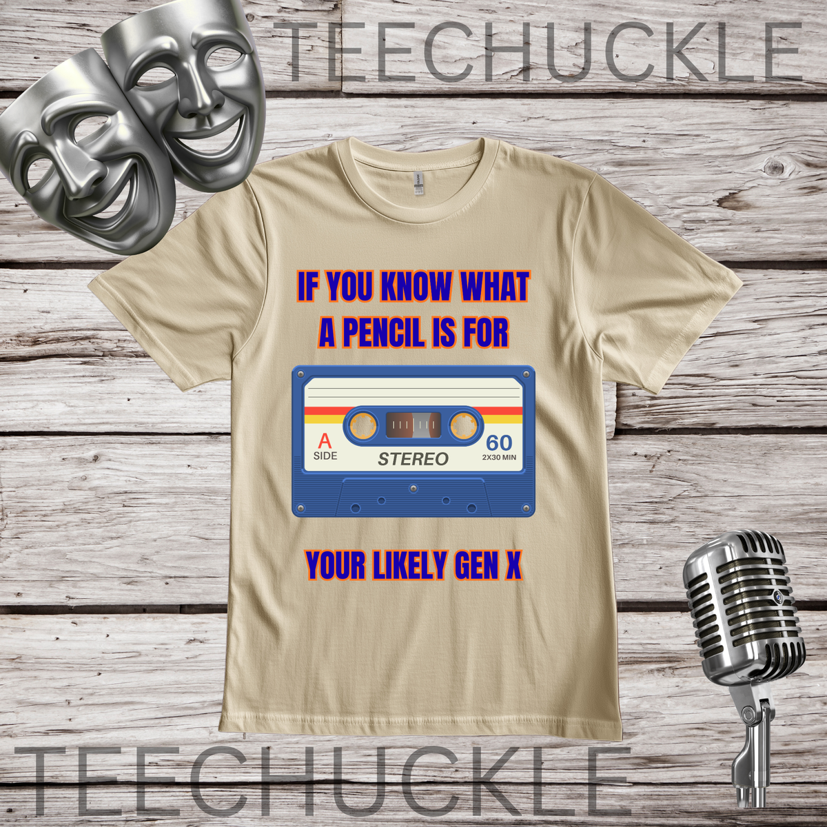 A sand graphic t-shirt displayed on a rustic wood background, featuring a retro cassette tape design with the text 'IF YOU KNOW WHAT A PENCIL IS FOR YOUR LIKELY GEN X'. The image includes decorative props like silver comedy and tragedy masks, a vintage microphone.