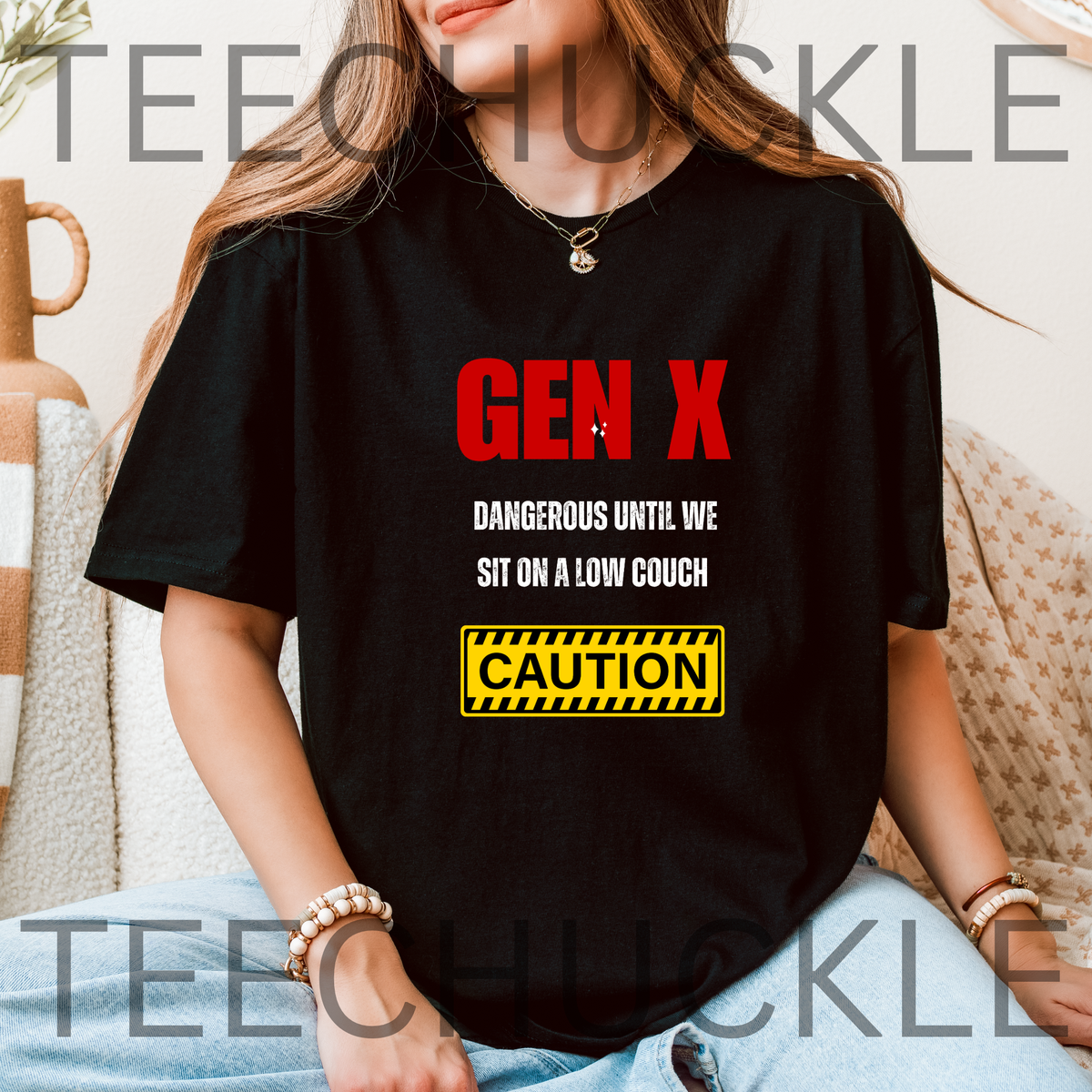 A woman wearing a black graphic t-shirt with the text 'GEN X DANGEROUS UNTIL WE SIT ON A LOW COUCH' and a yellow 'CAUTION' sign, set against a cozy indoor background