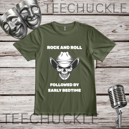 An green graphic t-shirt featuring a skull wearing a cowboy hat design with the text 'rock and roll, followed by early bedtime'. The t-shirt is displayed on a rustic wood background with silver-themed props including a vintage microphone, theatrical masks, and a metal stand.