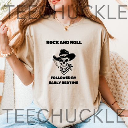 A woman wearing a sand graphic t-shirt with a black skull cowboy print and the text 'ROCK AND ROLL FOLLOWED BY EARLY BEDTIME'.