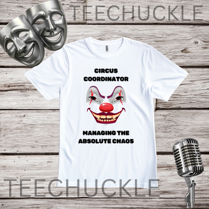 A white graphic t-shirt featuring a creepy clown face and the text 'CIRCUS COORDINATOR' and 'MANAGING THE ABSOLUTE CHAOS' in black. The t-shirt is displayed on a rustic wood background with silver theater-themed props (a comical mask and a vintage microphone) and a prominent 'TEECHUCKLE' watermark overlay.