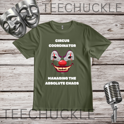 An green graphic t-shirt displayed on a rustic wood background, featuring a clown face illustration and the text 'CIRCUS COORDINATOR' and 'MANAGING THE ABSOLUTE CHAOS'. The t-shirt is styled with theatrical comedy and tragedy masks, a vintage microphone