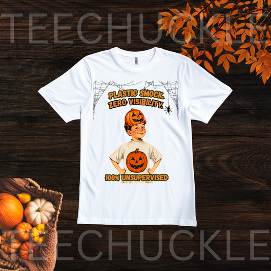 A white shirt on wooden boards surrounded by autum leaves and pumpkins. The shirt has boy wearing a plastic smock with a pumpkin on the shirt and on his head with the text "PLASTIC SMOCK< ZERO VISABILITY 100% UNSUPERVISED