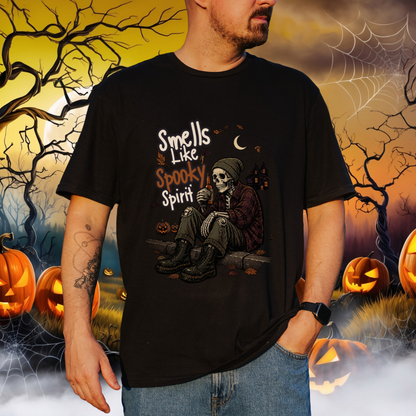 A man wearing a black graphic t-shirt with a Halloween design featuring a skeleton sitting and the text 'Smells Like Spooky Spirit'. The background is a digital illustration of a spooky Halloween scene with pumpkins, cobwebs, and a full moon.