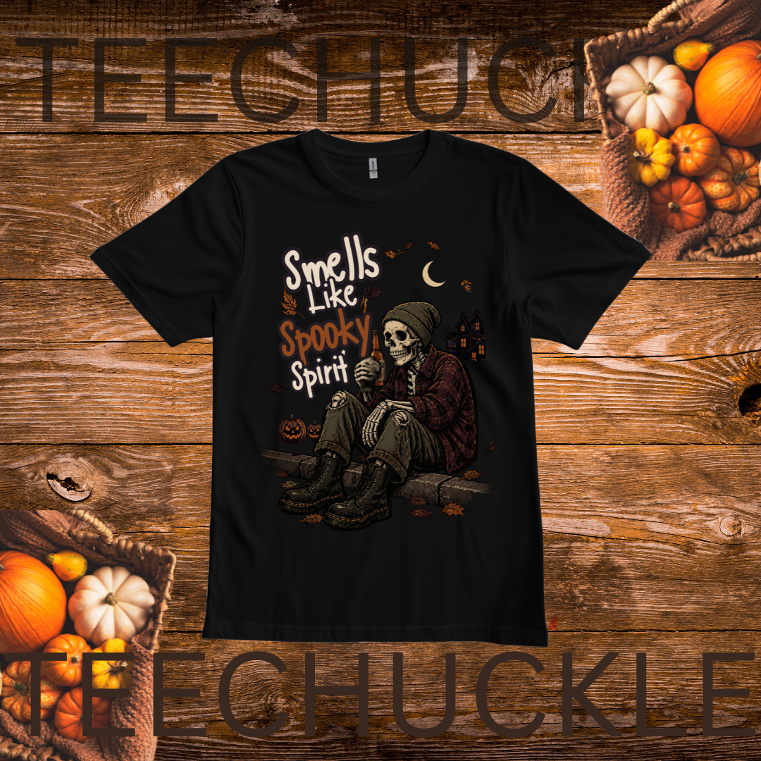 A black short-sleeve graphic T-shirt laid flat on a rustic wooden background with pumpkins and autumn props around it. The shirt features a Halloween-themed illustration of a seated skeleton figure with the text 'Smells Like Spooky Spirit.