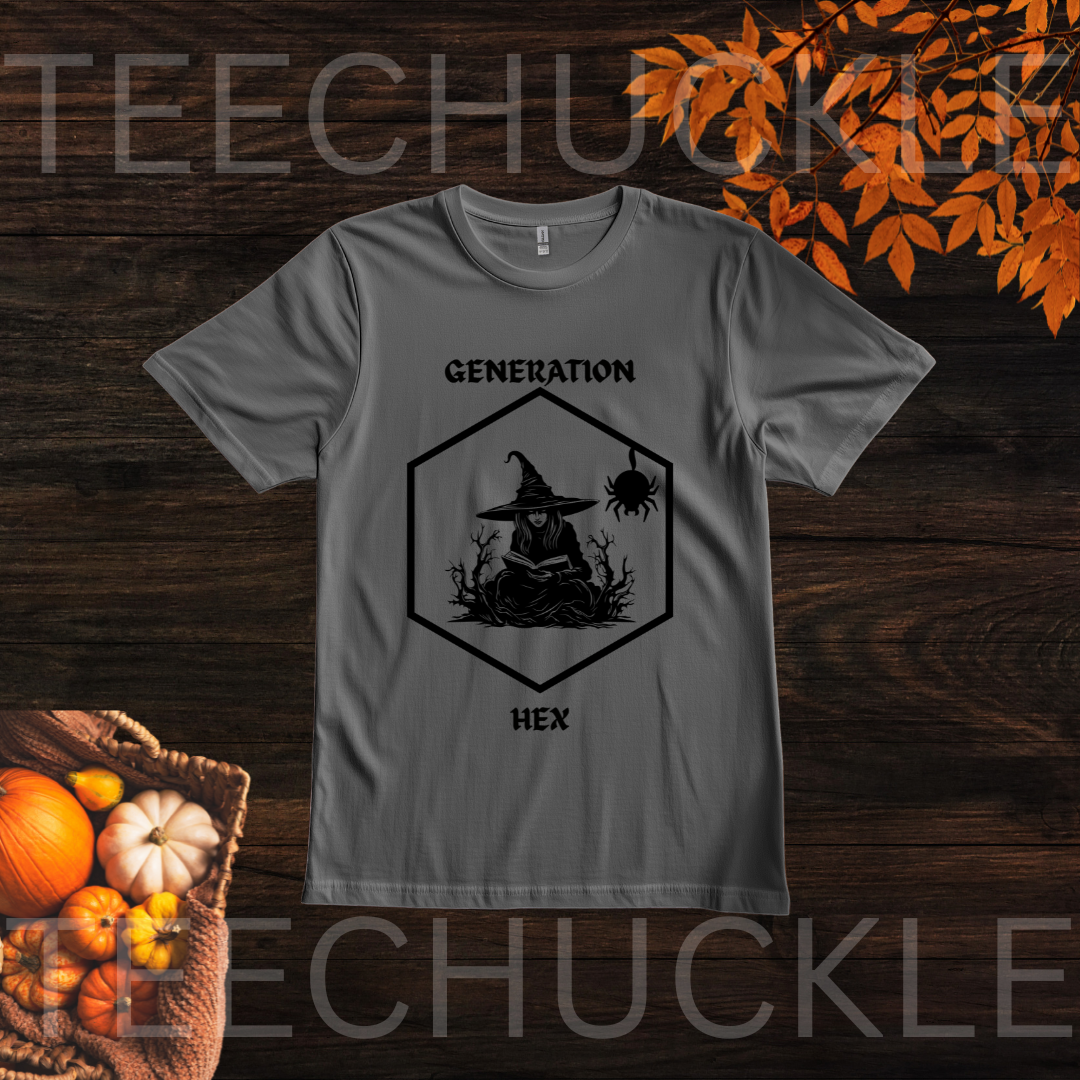A gray short-sleeve graphic T-shirt laid flat on a dark wood background with autumn leaves and pumpkins around it. The shirt has a black hexagonal witch illustration with the words 'GENERATION' above and 'HEX' below.