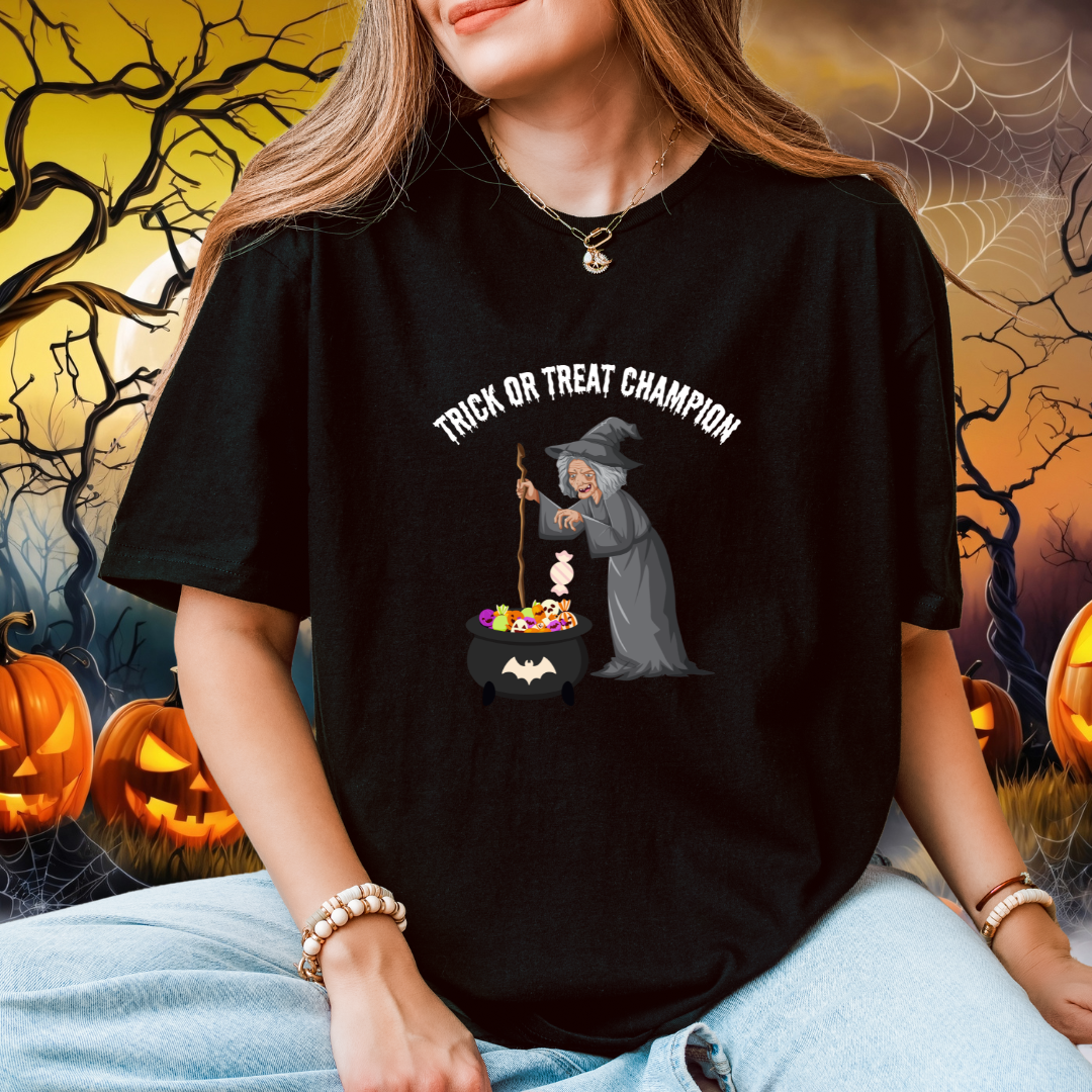A woman wearing an oversized black graphic t-shirt with a Halloween witch design. The graphic shows a witch stirring a cauldron of candy with the text 'TRICK OR TREAT CHAMPION'.