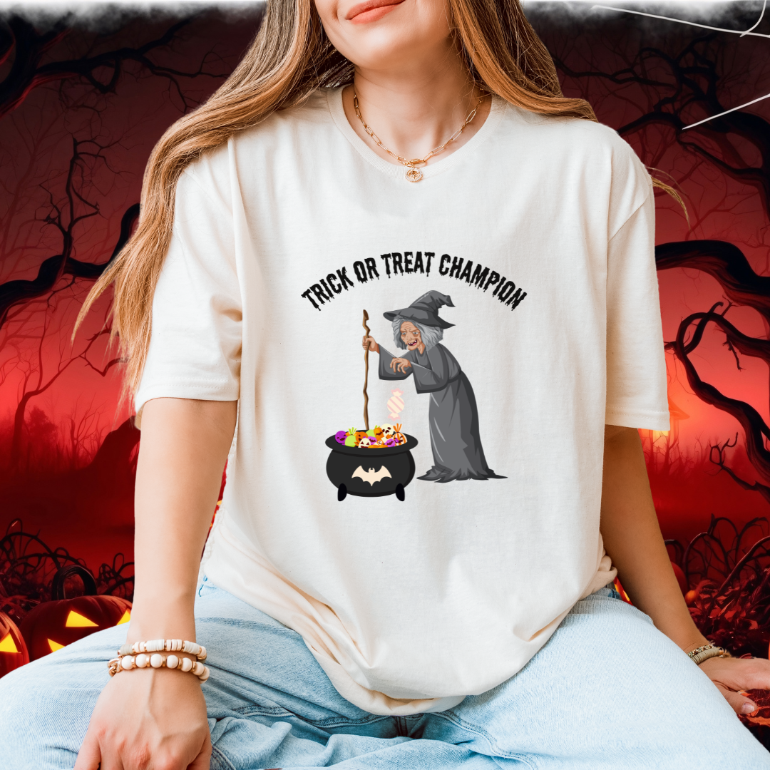 A woman wearing an oversized off-white graphic t-shirt with a 'Trick or Treat Champion' witch illustration, paired with light blue jeans, set against a spooky Halloween-themed background.