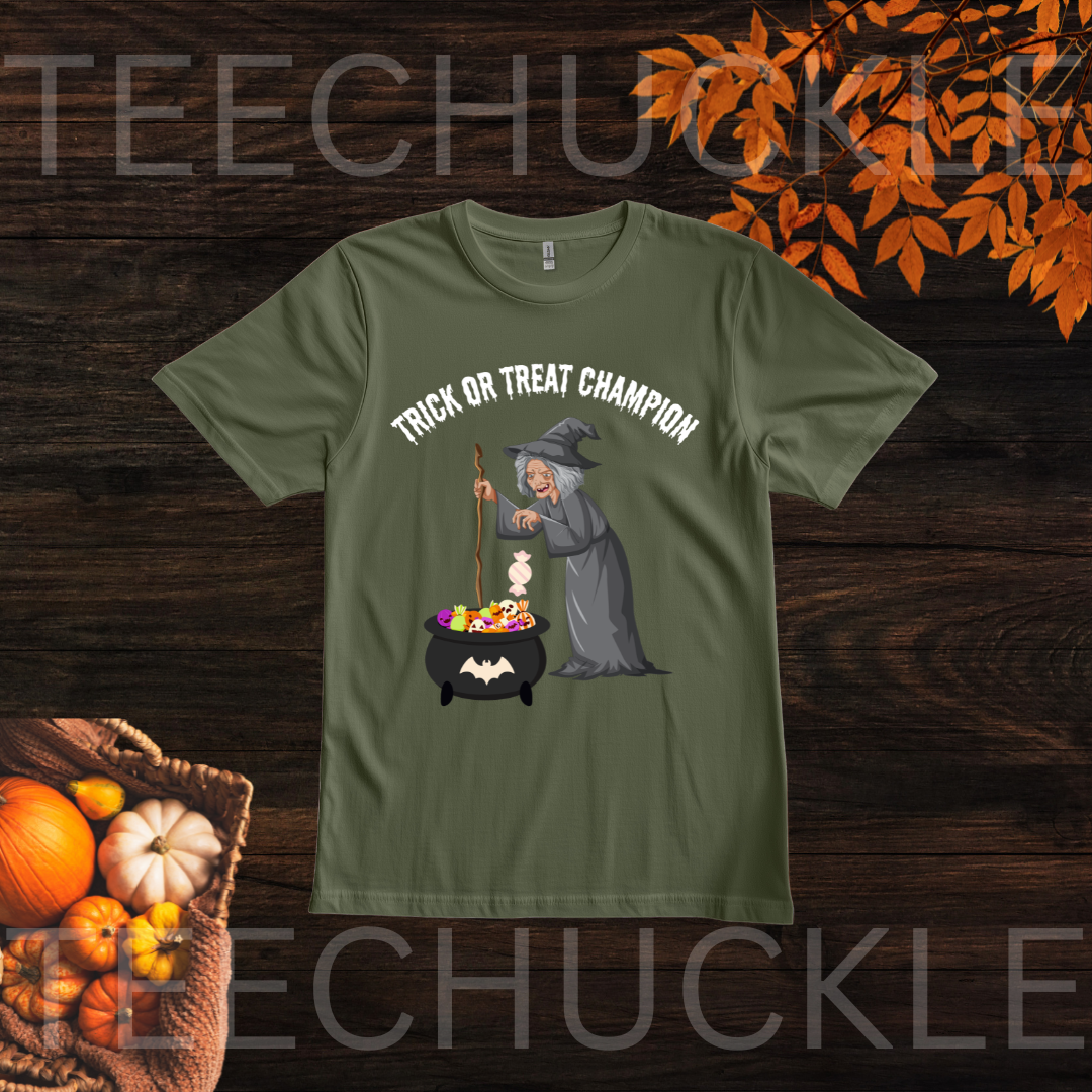 A green short-sleeve t-shirt with a 'Trick or Treat Champion' witch graphic, displayed on a dark wood background with autumn leaves and pumpkins.