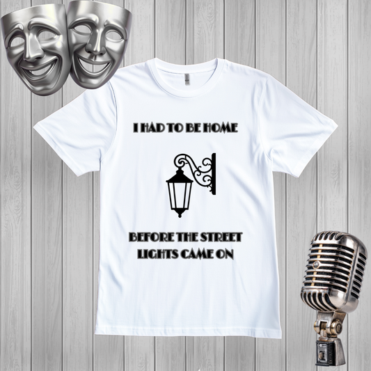 A white graphic t-shirt with a black printed design that reads 'I HAD TO BE HOME BEFORE THE STREET LIGHTS CAME ON' with a street lamp illustration, 