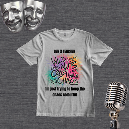 A lgray graphic t-shirt displayed on a dark gray textured background, styled with silver comedy masks in the top-left corner and a vintage silver microphone in the bottom-right corner. The t-shirt features a colorful, hand-drawn style graphic with the words 'WILD CRAZY CHAOS NUTS' in various colors, with 'GEN X TEACHER' above and 'I'm just trying to keep the chaos colourful' below.