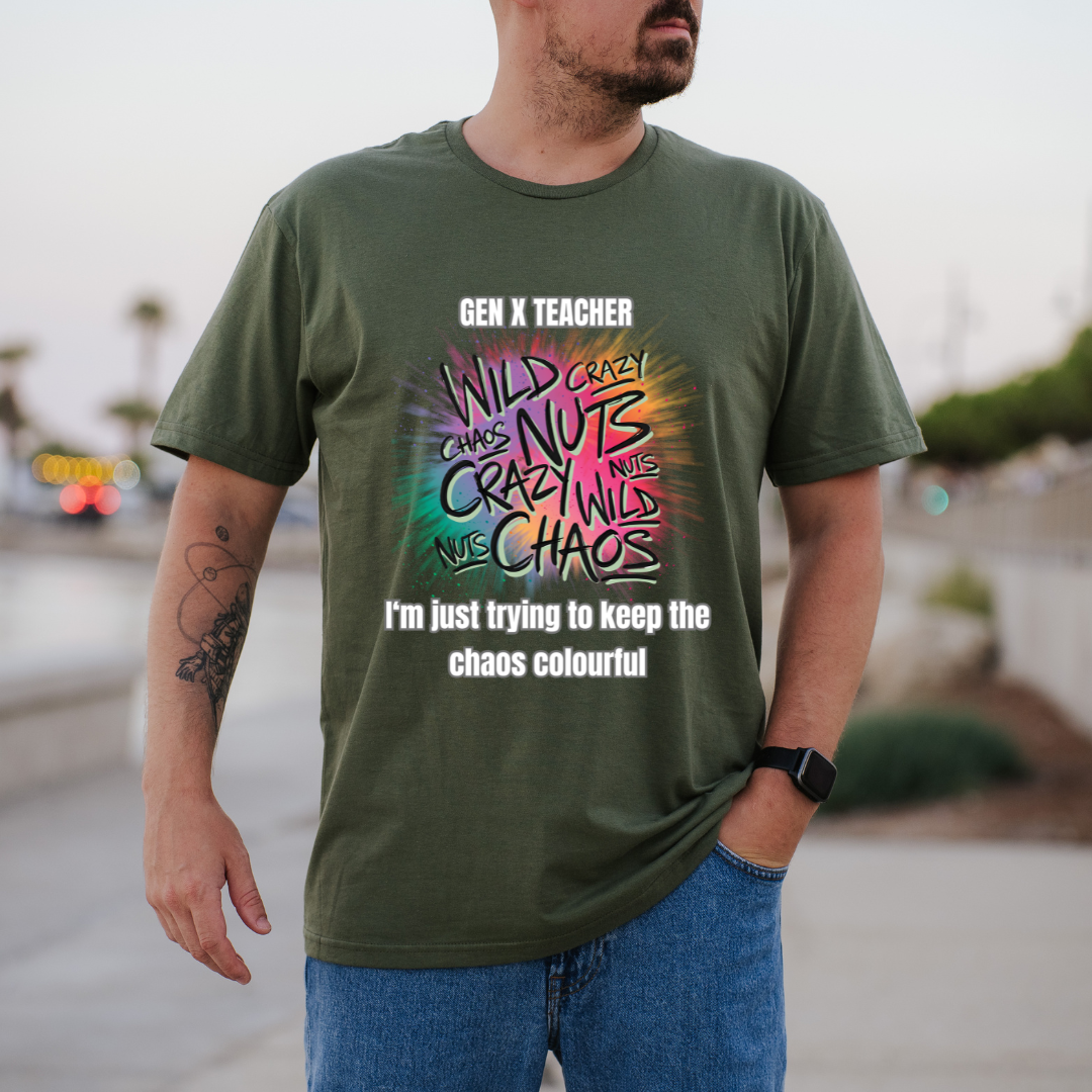 A man wearing a green graphic t-shirt with a colorful 'Gen X Teacher' design, paired with blue jeans, standing outdoors on a blurred street background.