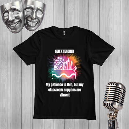 A black short-sleeve graphic T-shirt displayed on a light gray wood plank background, with two silver theater masks in the top left and a vintage silver microphone in the bottom right. The shirt features a colorful classroom-supplies illustration and the text 'GEN X TEACHER My patience is thin, but my classroom supplies are vibrant'.