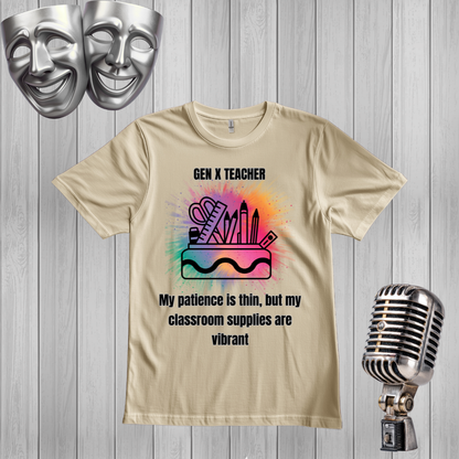 A sand graphic t-shirt displayed on a gray wood-plank background, styled with silver comedy and tragedy masks in the top-left corner and a vintage silver microphone on the bottom-right. The t-shirt features a colorful school supplies illustration and the text 'GEN X TEACHER My patience is thin, but my classroom supplies are vibrant'.