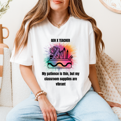 A woman wearing a white graphic t-shirt with a colorful paint splatter design and the text 'GEN X TEACHER My patience is thin, but my classroom supplies are vibrant'. She is sitting on a beige sofa with a patterned throw blanket.