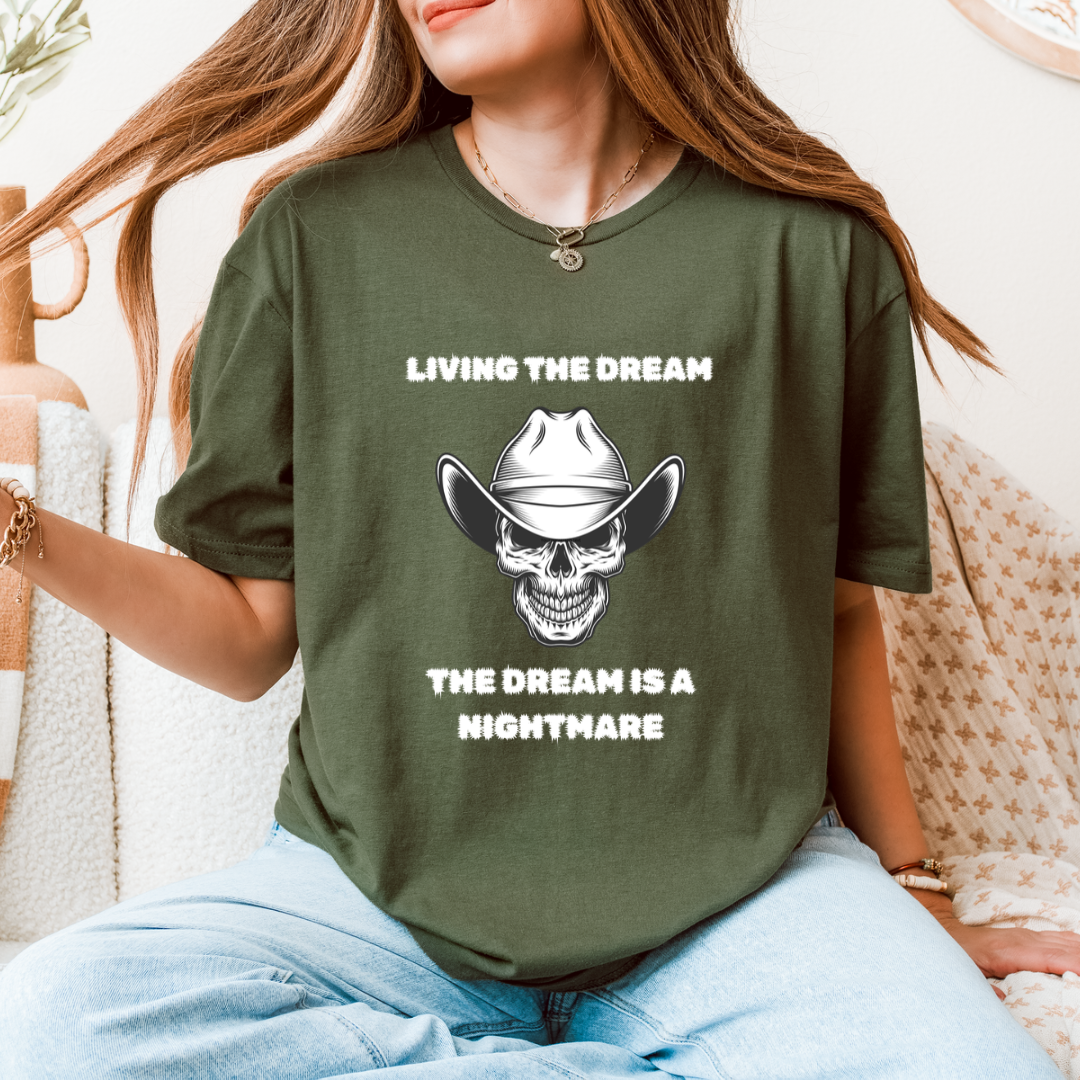 A woman wearing a green graphic t-shirt with a white and black cowboy skull design and the text 'LIVING THE DREAM THE DREAM IS A NIGHTMARE'.