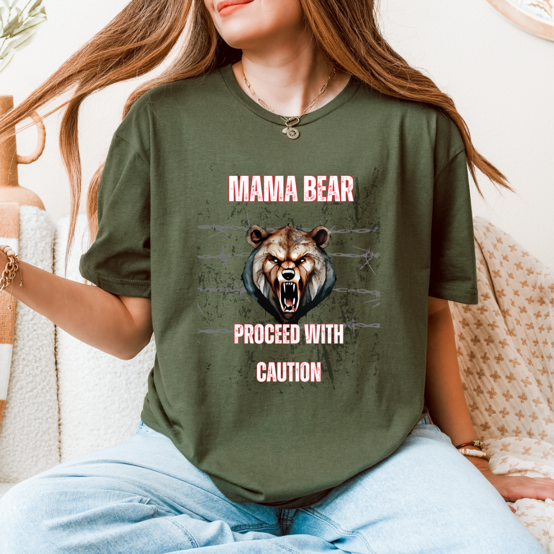 A woman wearing a green graphic t-shirt with a bear illustration and the text 'MAMA BEAR PROCEED WITH CAUTION'.