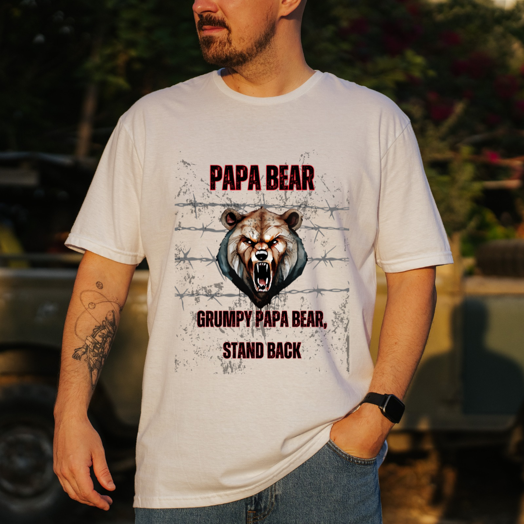 A man wearing a white graphic t-shirt with a 'Papa Bear' design, standing outdoors in front of a blurred vehicle.
