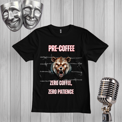 A black graphic t-shirt displayed on a light gray wood plank background, flanked by two silver comedy masks on the top left and a vintage silver microphone on the bottom right. The t-shirt features a graphic of a snarling bear with glowing orange eyes, barbed wire, and the text 'PRE-COFFEE' and 'ZERO COFFEE, ZERO PATIENCE' in pink and white.