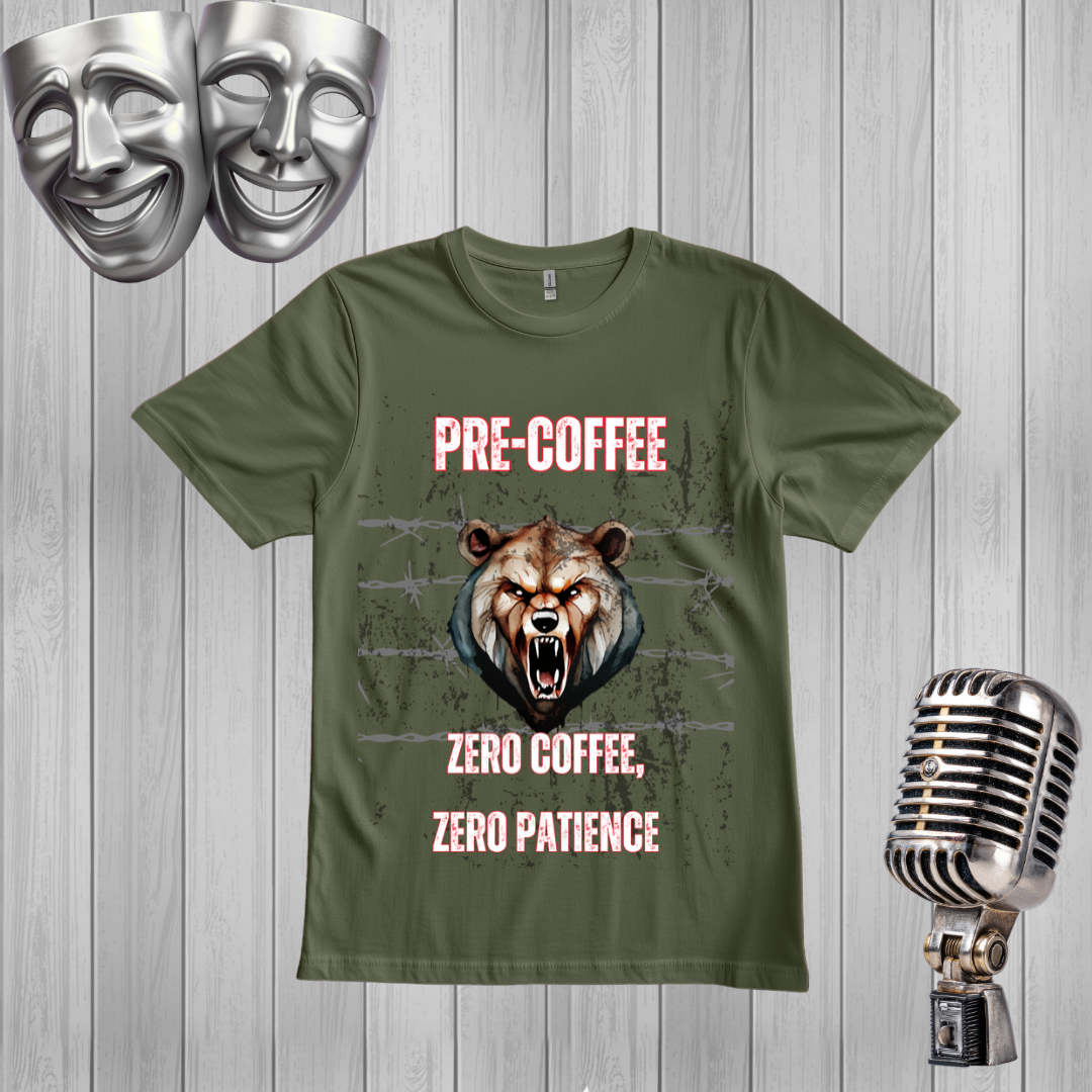 A green graphic t-shirt displayed on a light gray wood plank background, styled with a silver vintage microphone on the right, two silver comedy masks at the top left, and a distressed brown bear graphic with the text 'PRE-COFFEE ZERO COFFEE, ZERO PATIENCE'.