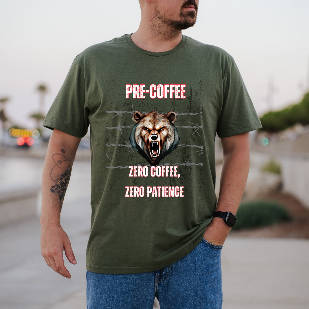 A man wearing a green graphic t-shirt with a bear graphic and the text 'PRE COFFEE ZERO COFFEE ZERO PATIENCE' on the front, set against a blurred outdoor background.