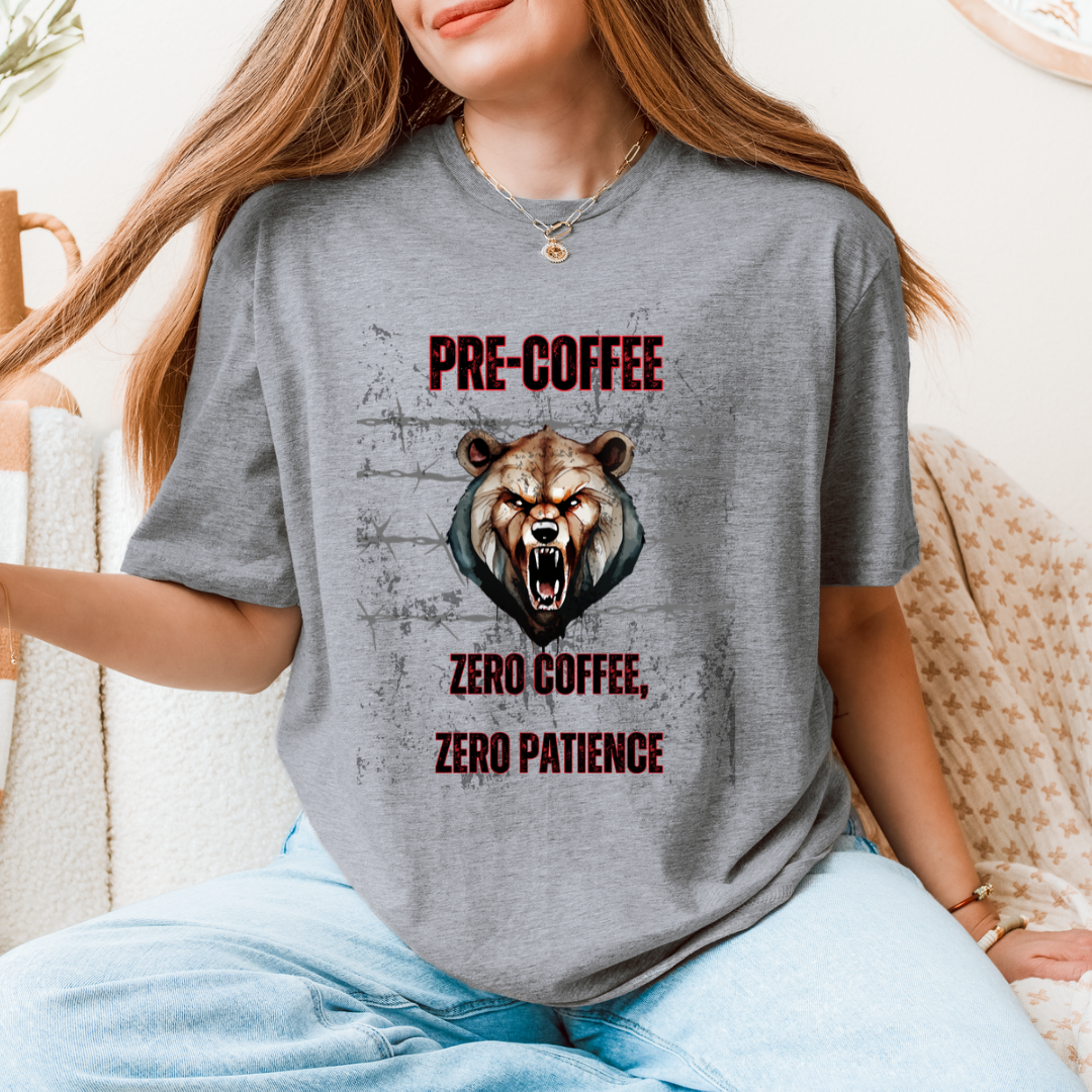 A woman wearing a gray graphic t-shirt with a roaring bear illustration and the text 'PRE-COFFEE ZERO COFFEE, ZERO PATIENCE'.