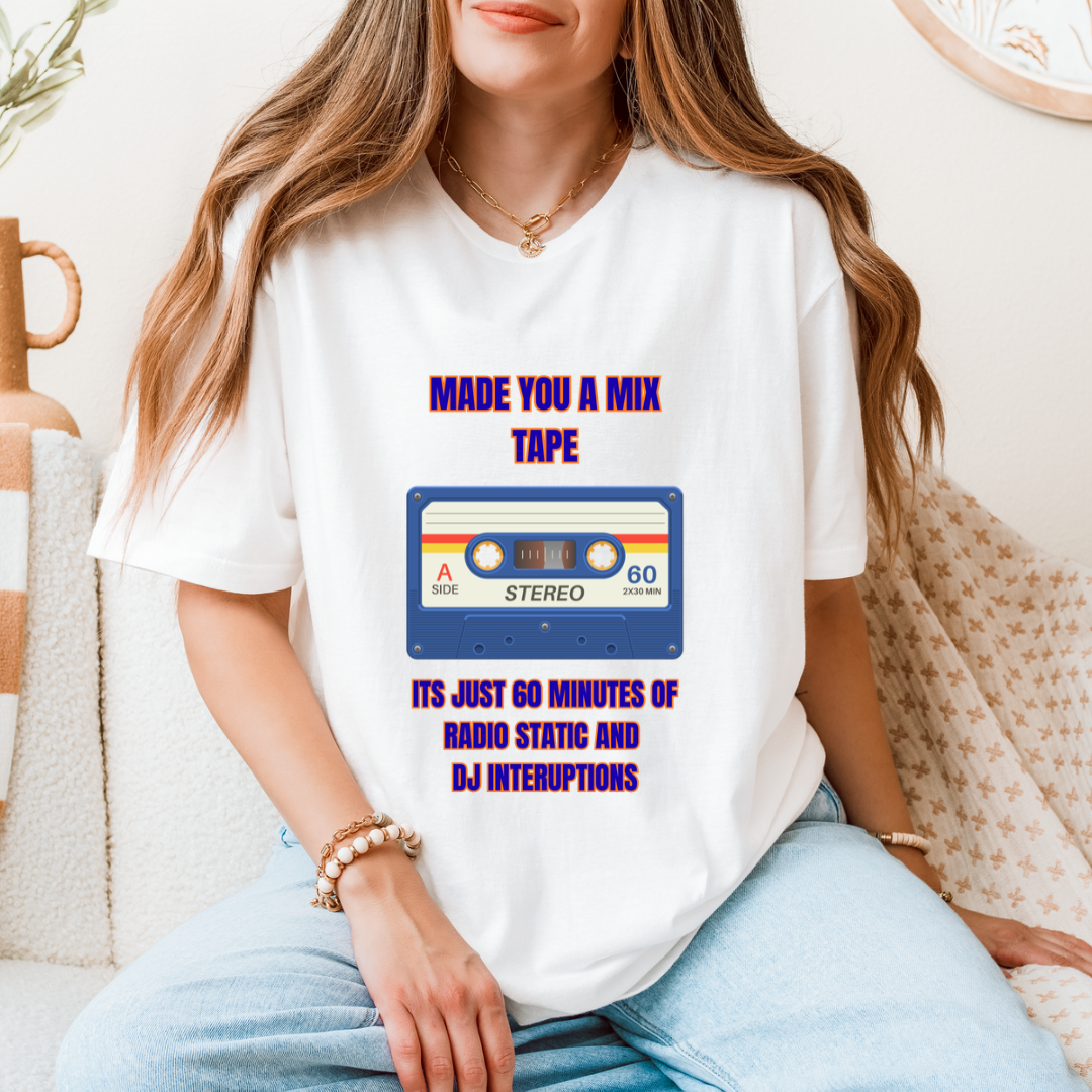 A woman wearing a white graphic t-shirt with a retro cassette tape design and purple text that reads 'MADE YOU A MIX TAPE ITS JUST 60 MINUTES OF RADIO STATIC AND DJ INTERRUPTIONS'.