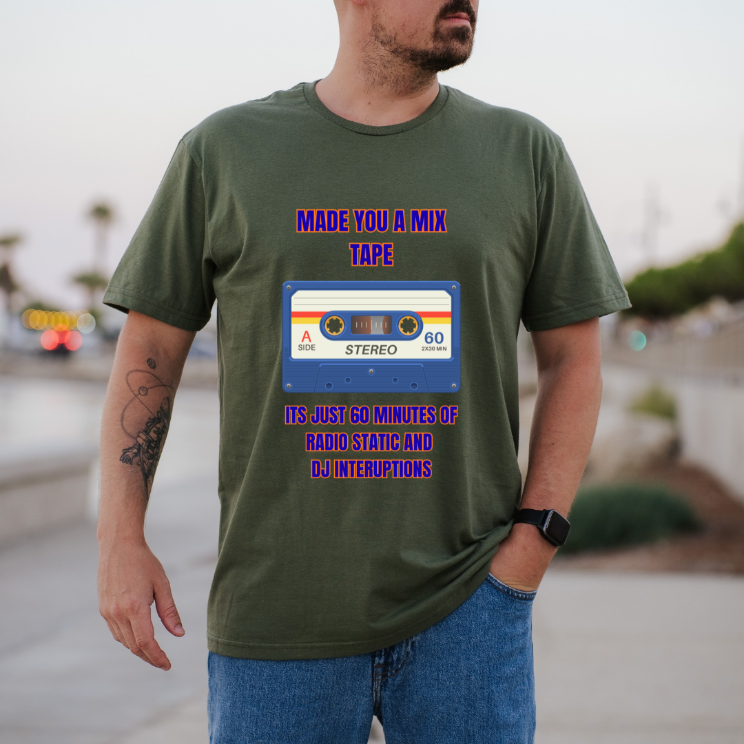 A man wearing a green t-shirt with a retro cassette tape graphic that reads 'MADE YOU A MIX TAPE' and 'ITS JUST 60 MINUTES OF RADIO STATIC AND DJ INTERUPTIONS'.