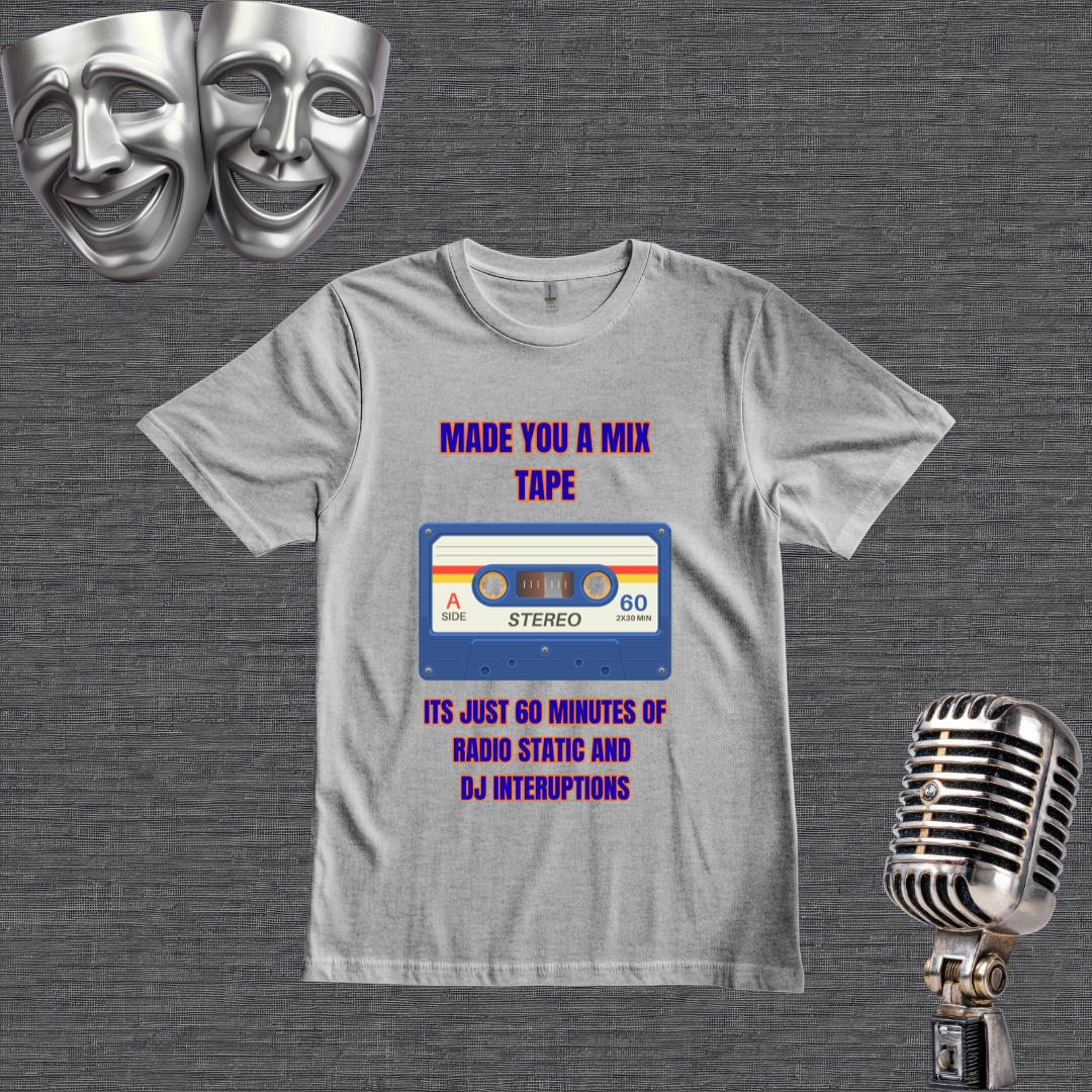 A gray graphic t-shirt displayed flat on a dark gray textured background, flanked by two silver comedy masks at the top and a vintage silver microphone at the bottom right. The t-shirt features a retro cassette tape graphic with the text 'MADE YOU A MIX TAPE' in purple and blue, and 'ITS JUST 60 MINUTES OF RADIO STATIC AND DJ INTERUPTIONS' in blue and purple.