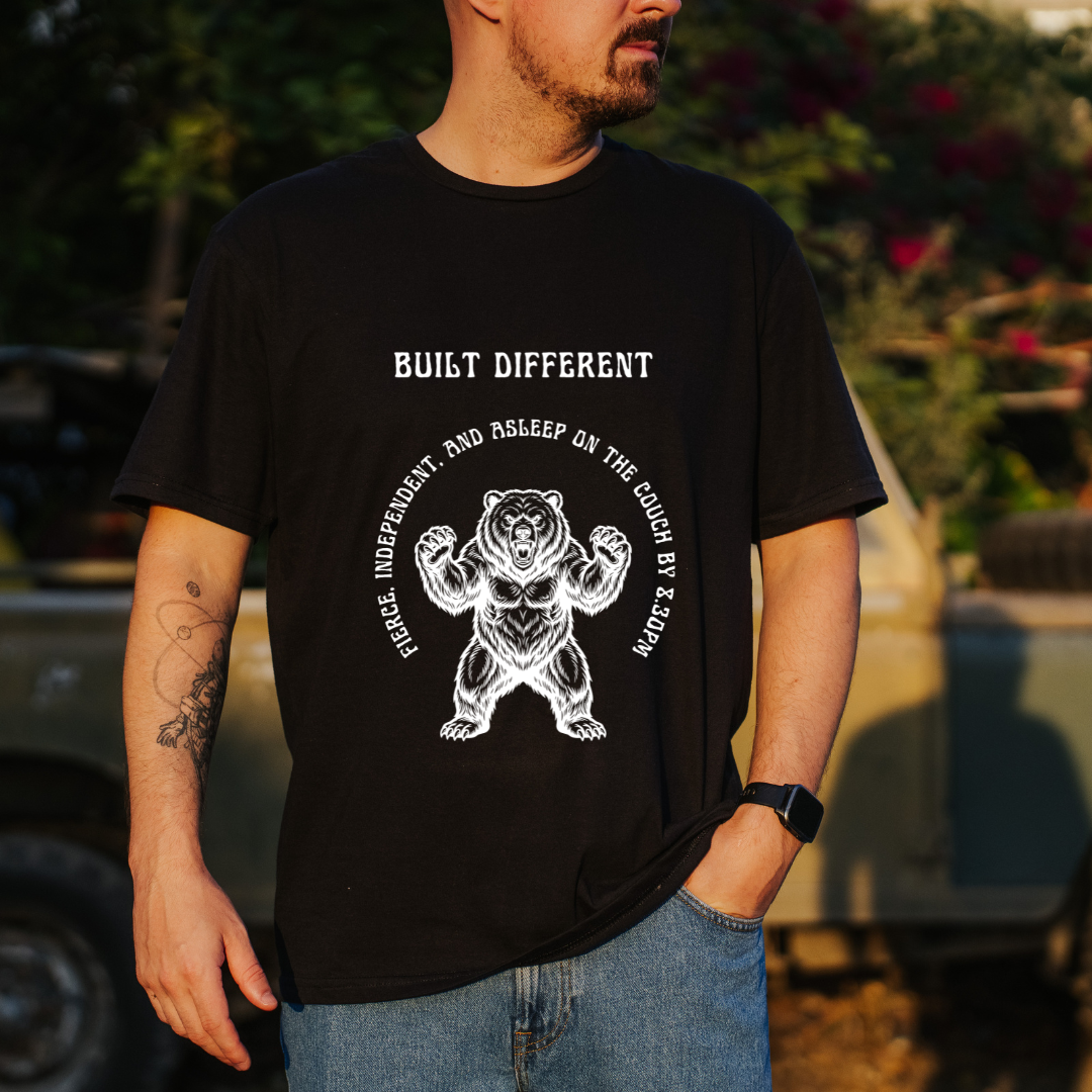 A man wearing a black graphic t-shirt with a white bear design and the text 'BUILT DIFFERENT' 