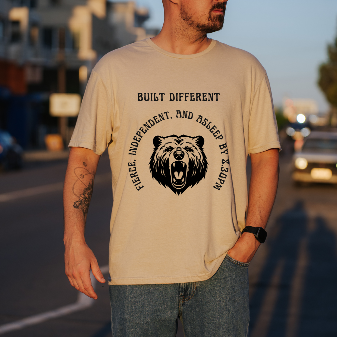 A man wearing a sand graphic t-shirt with a black bear design and the text 'BUILT DIFFERENT'