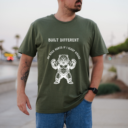 A green short-sleeve graphic t-shirt  The t-shirt features a black graphic of a roaring bear with the text 'MY BACK IF I SLEEP WRONG' and 'BUILT DIFFERENT' above it.