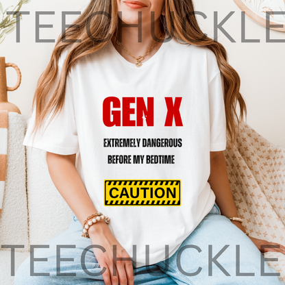 A white graphic t-shirt featuring the text 'GEN X EXTREMELY DANGEROUS BEFORE MY BEDTIME' in red and black, and a yellow caution-style box. Silver theater masks and a vintage microphone are placed around the shirt